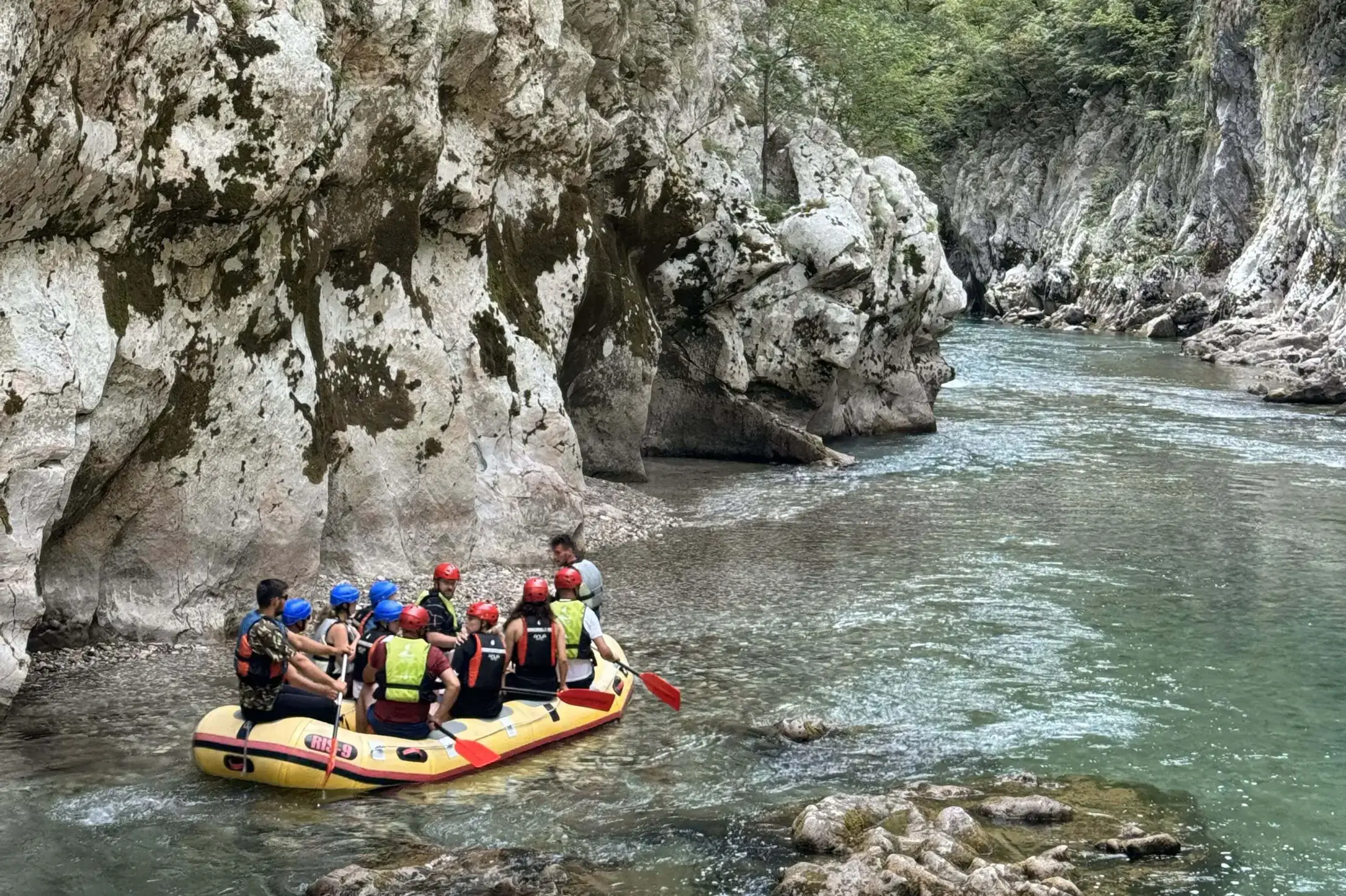 Guests rafting between limestone canyon walls on the Neretva River