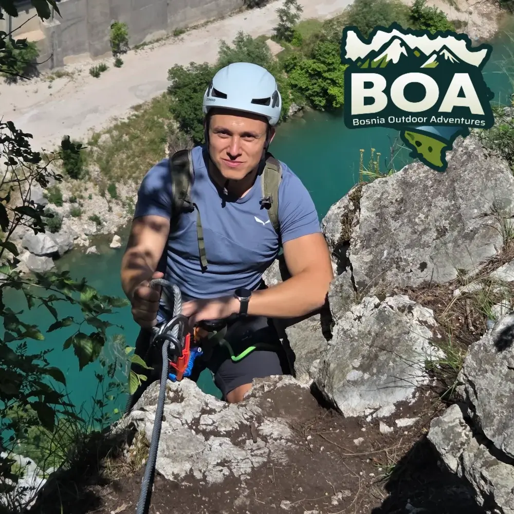Emir climbing a via ferrata above a mountain lake in Bosnia and Herzegovina